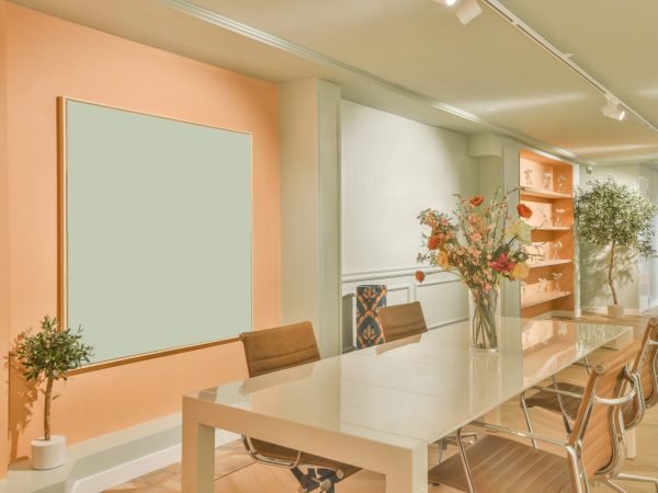 Table with chairs and flowers located near lounge area spacious room of contemporary apartment