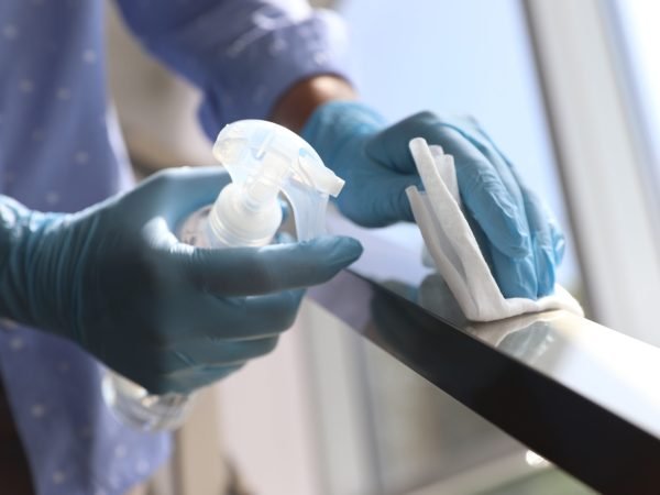 Woman in latex gloves cleaning railing with wet wipe and detergent indoors, closeup